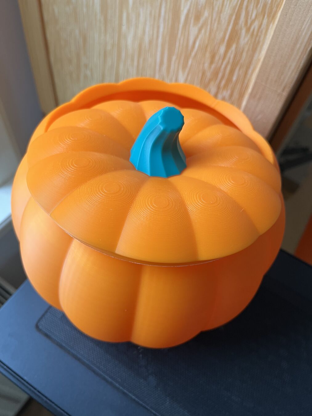 A bowl in the shape of a pumpkin with the lid a bit off