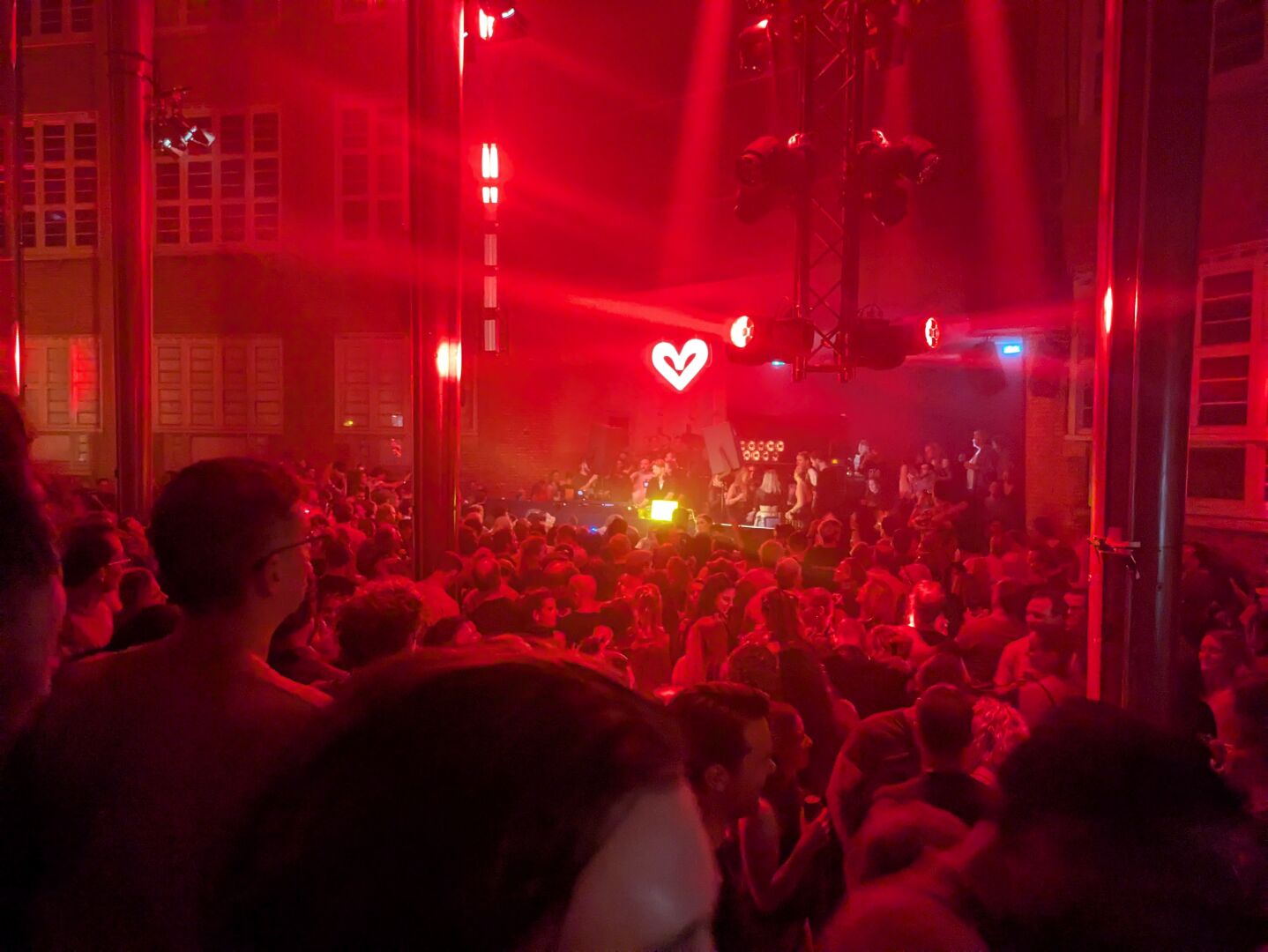 Het Sierraad in Amsterdam vol mensen in rood licht met een lichtgevens hart boven het podium.