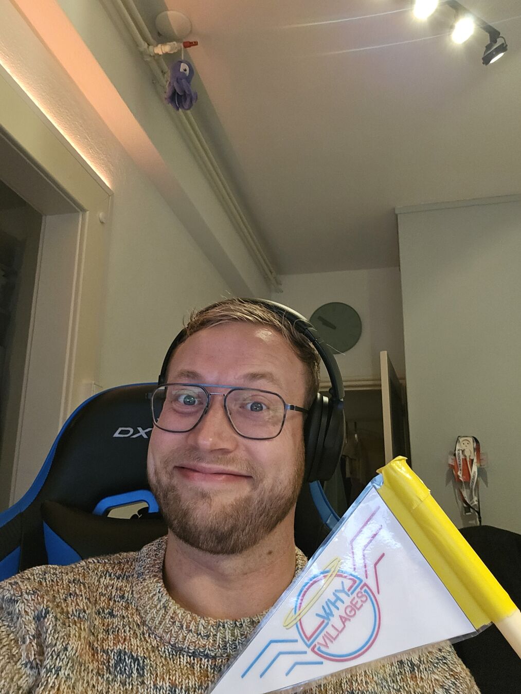 Smiling dude inside while holding a flag with a WHY2025 villages logo that used to be on the back of bikes at the campsite